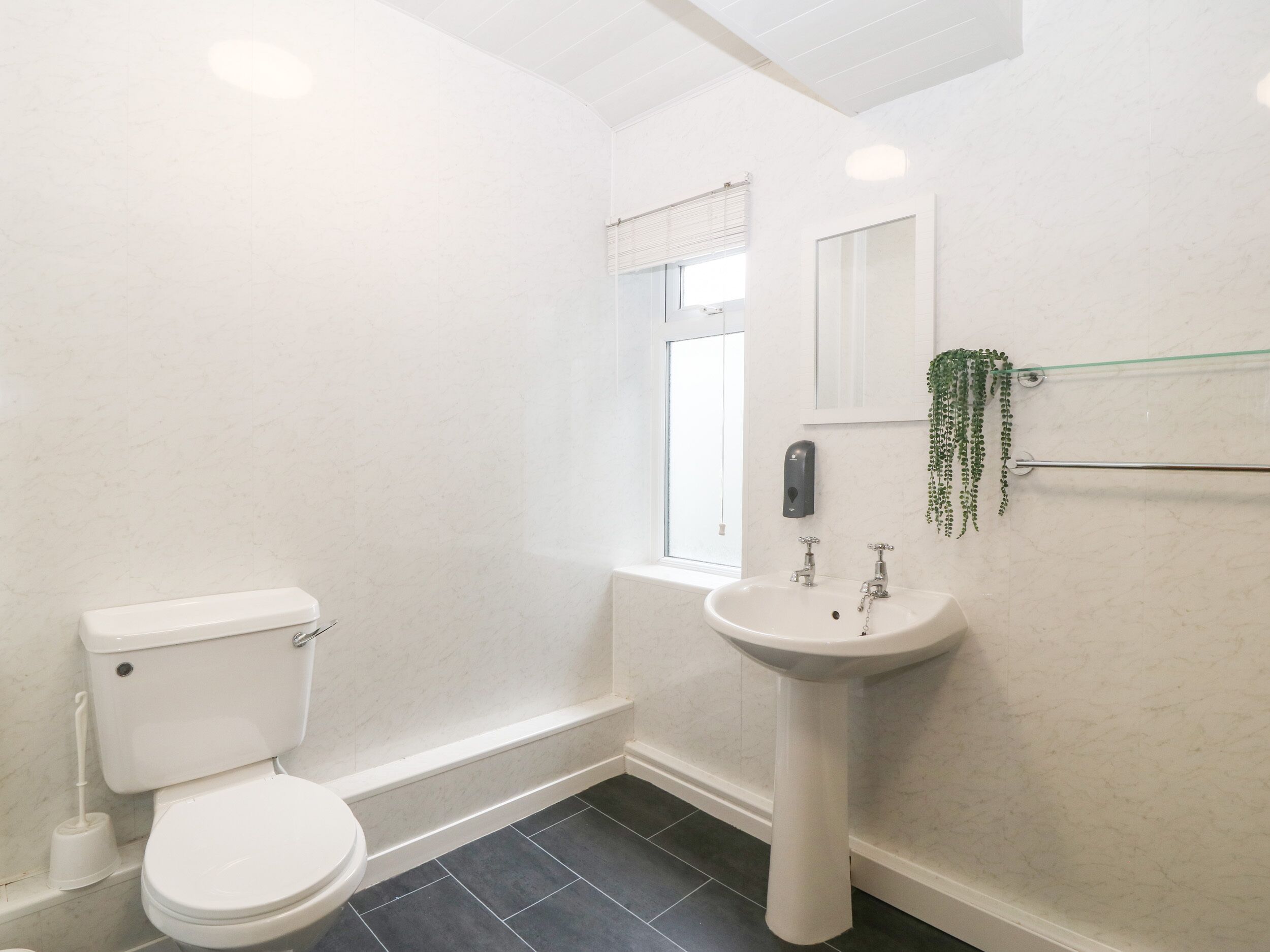 A bathroom with a toilet, sink, and window.