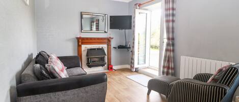 Una sala de estar con chimenea, un sofá, un sillón a rayas y un televisor.
