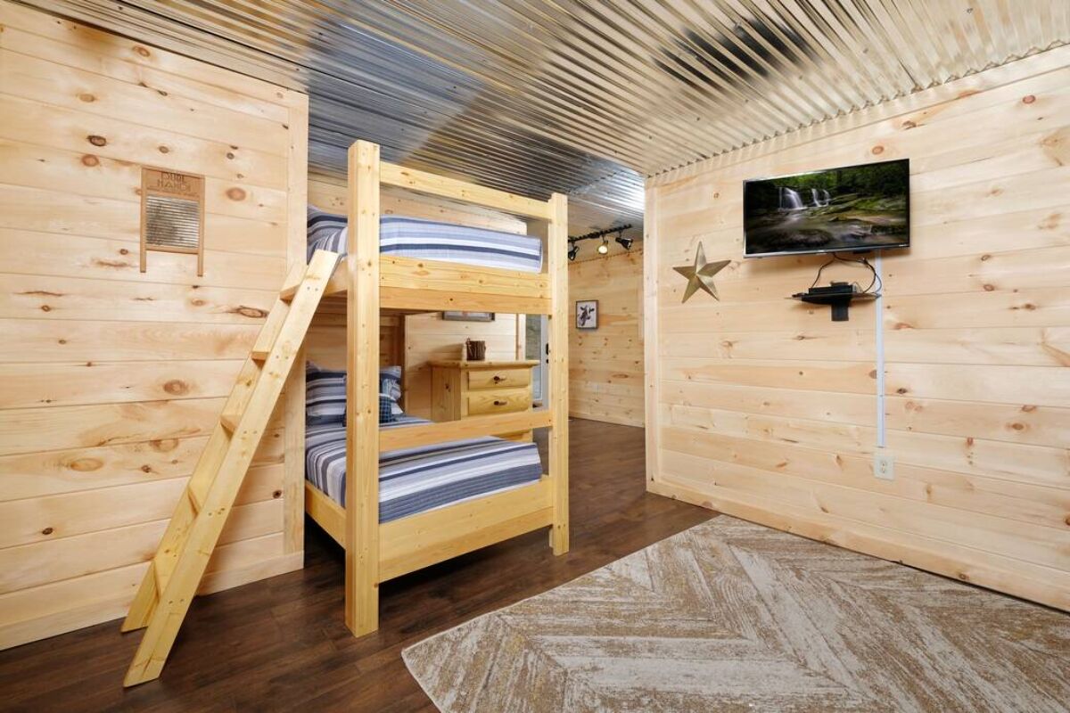 Una habitación tipo cabaña de madera con literas, televisión y una decoración con estrellas en la pared.