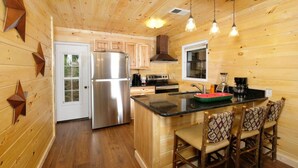 Cocina de cabaña de madera con refrigerador, estufa y asientos en la barra.