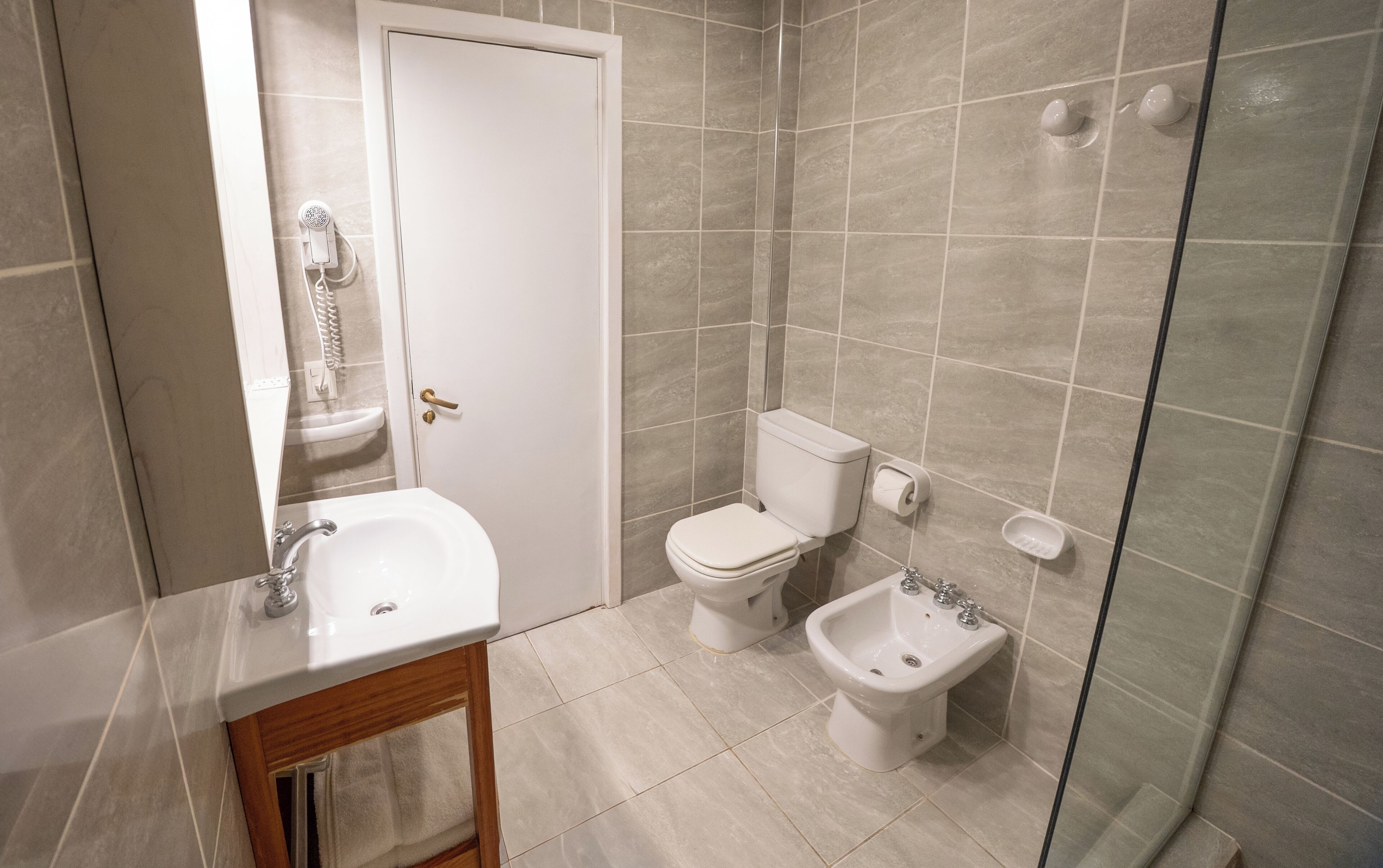 A bathroom with a sink, toilet, bidet, and shower.