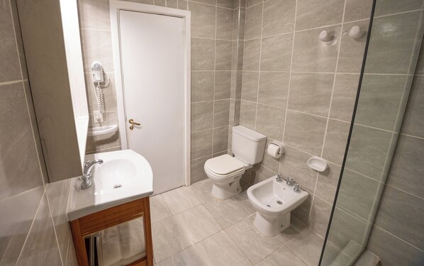 A bathroom with a sink, toilet, bidet, and shower.