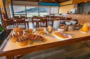 A buffet setup with various food items and a view of the outdoors. - Tolkeyén Ushuaia Hotel (Ushuaia)