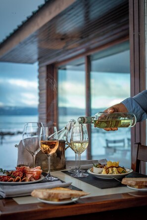 Una mesa con copas de vino, una botella sirviéndose y un plato de comida.