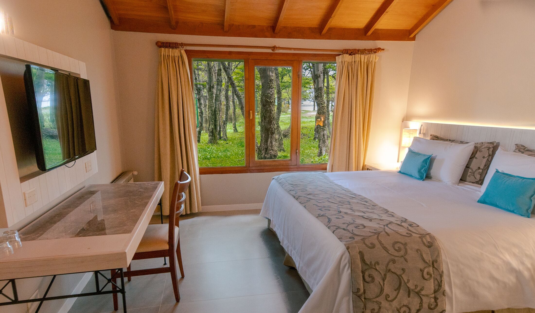 Um quarto com uma cama, uma escrivaninha e uma televisão.