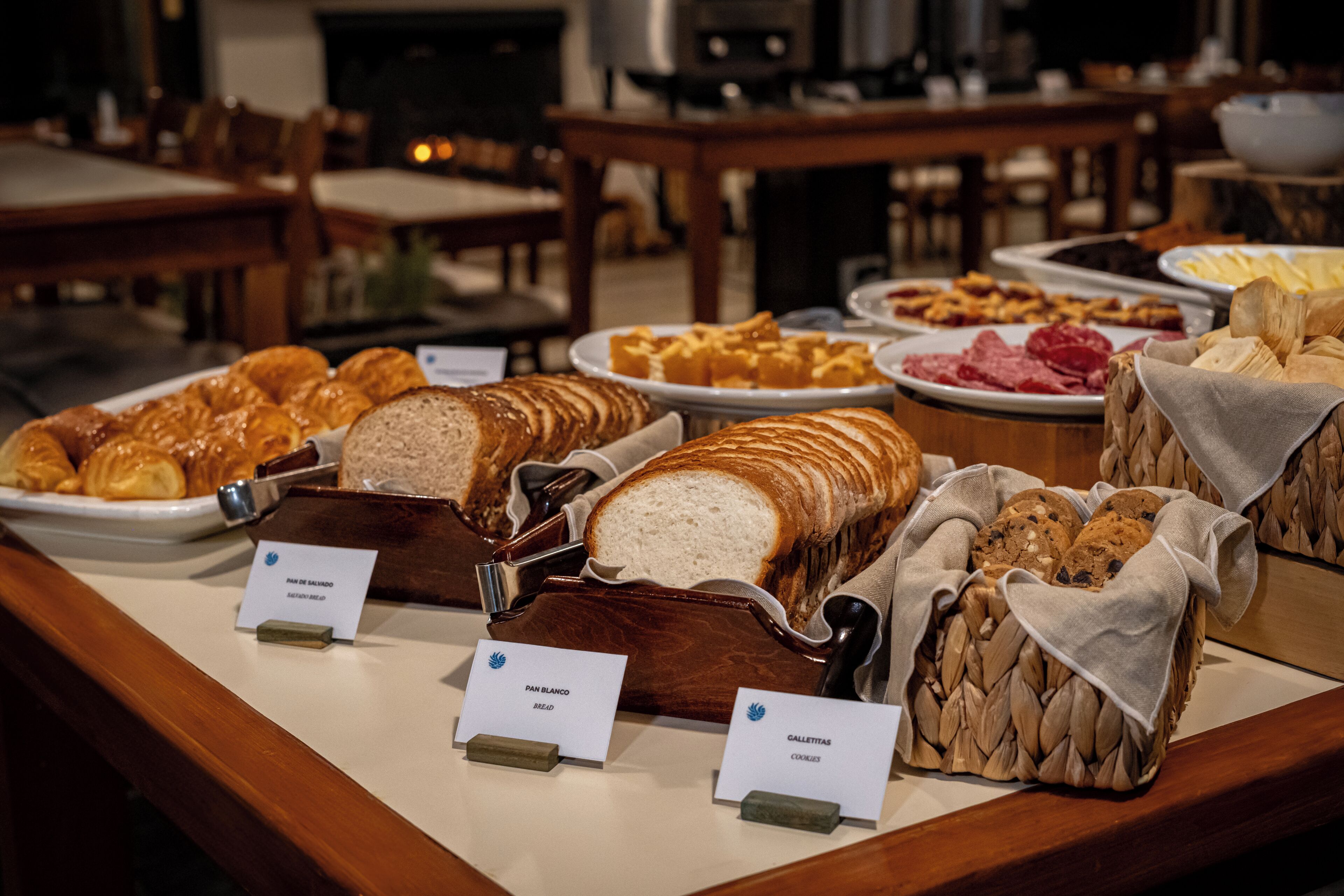 Een buffet met diverse broden en gebak, waaronder croissants en een groot brood.