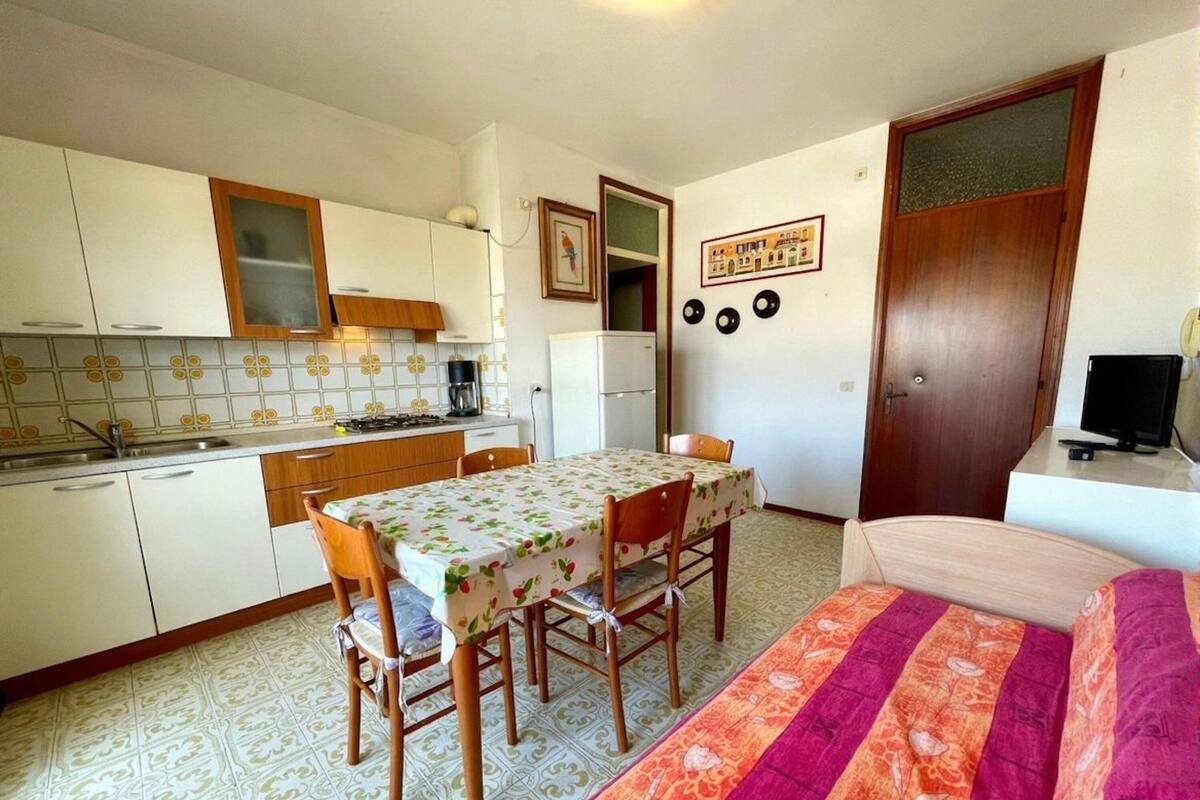 A compact kitchen with a dining table, chairs, and a small sofa.