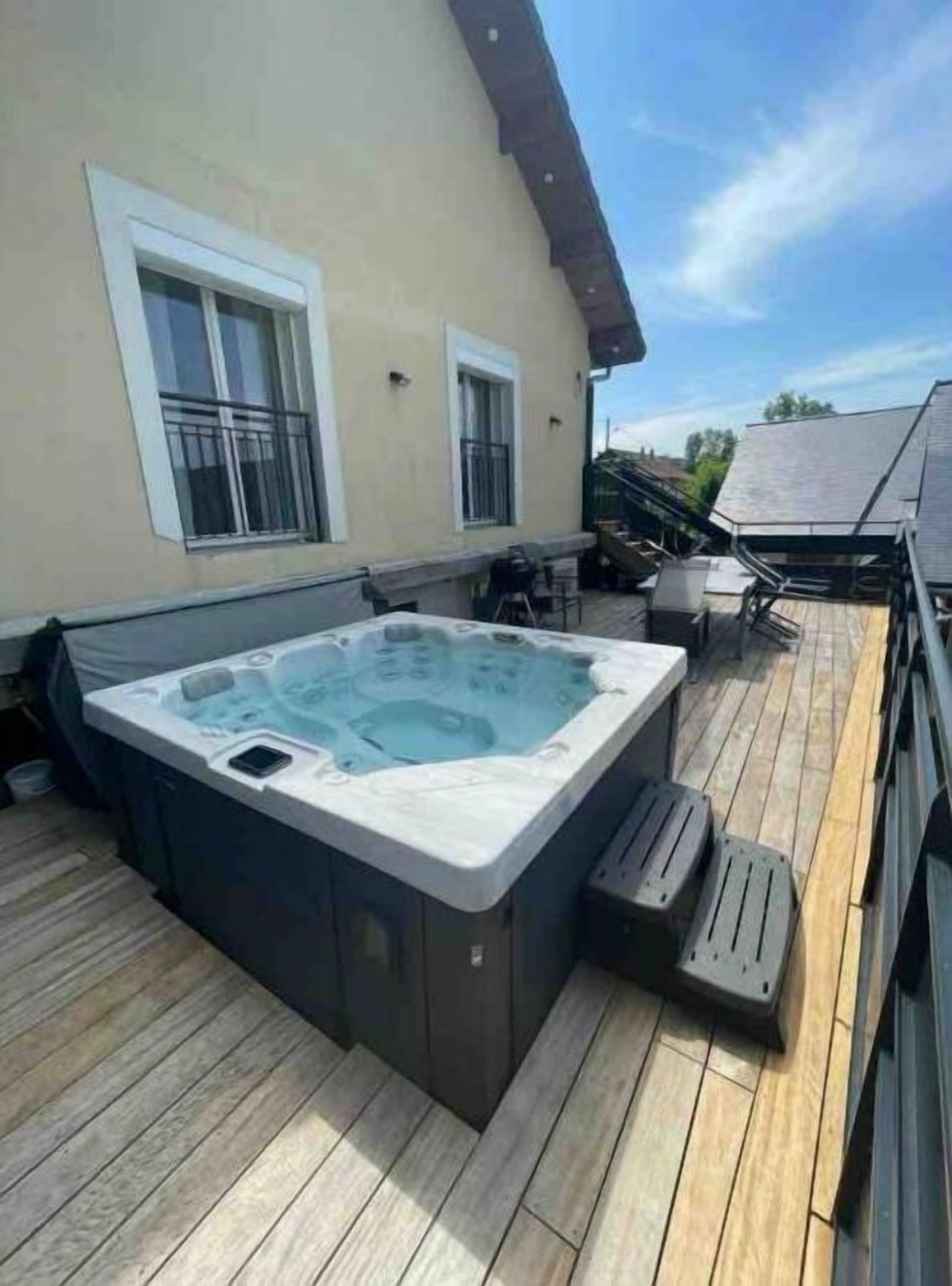 A hot tub on a wooden deck with a house in the background.