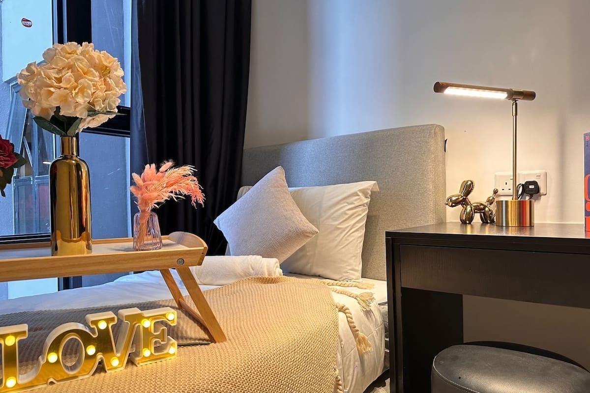 A modern bedroom with a bed, bedside table, lamp, and decorative items.