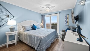 Ein Schlafzimmer mit Bett, Nachttisch, Kommode und Deckenventilator.