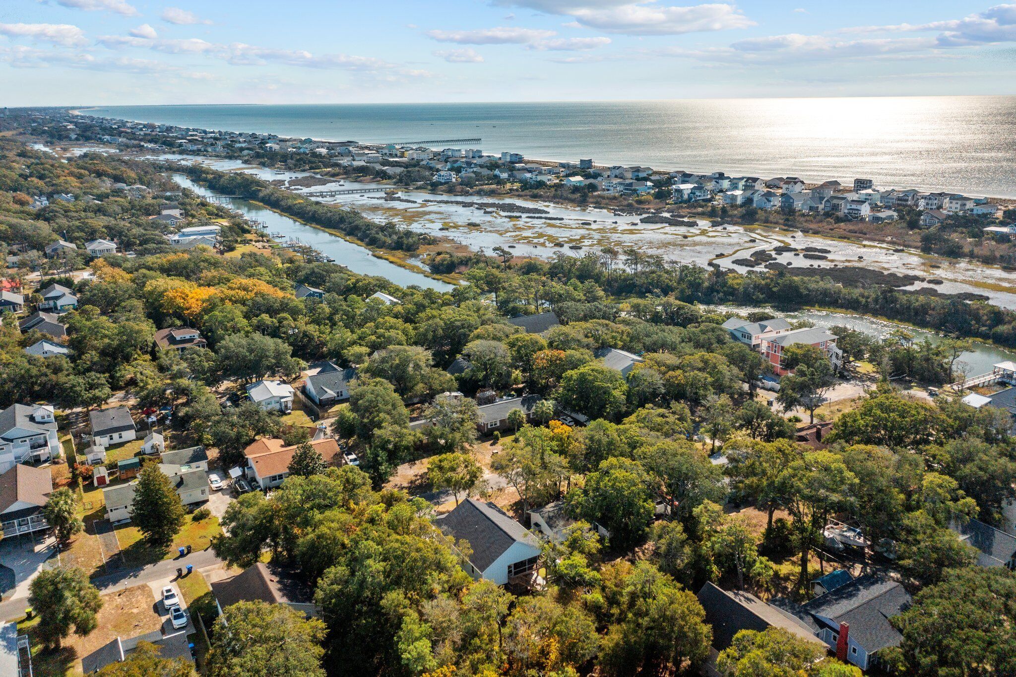 An aerial view of a coastal residential area with houses, a river, and a bridge.