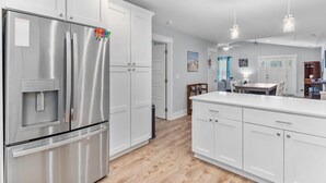 A modern kitchen with white cabinets, stainless steel appliances, and pendant lighting. - A Shore Escape! (Oak Island)