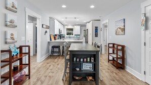 A modern kitchen with white cabinets, a wooden dining table, and pendant lighting. - A Shore Escape! (Oak Island)