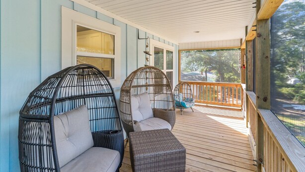 A covered porch with wicker chairs and a wooden deck. - A Shore Escape! (Oak Island)