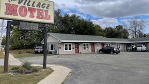 The Village Motel with a signboard, a parking lot, and a building with multiple windows and a red door. - The Village Motel (Eldora)