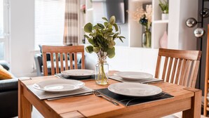 A dining table set with plates, a vase with green leaves, and a fork.
