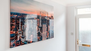 A cityscape painting on a wall, a door with frosted glass, and a light switch on the wall.