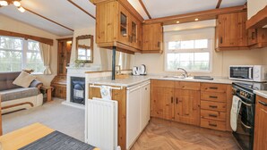 A compact kitchen with wooden cabinets, a built-in microwave, and a gas stove. - Little Malory (Launceston)