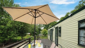 An outdoor patio with a table, chairs, and a large umbrella. - Little Malory (Launceston)