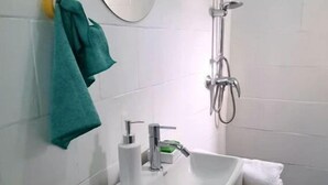 Ett badrum med ett vitt handfat, en spegel, en handdukshängare och en dusch.