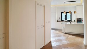 A modern kitchen with white cabinetry, a built-in oven, and pendant lighting. - Dizengoff Brique (Tel Aviv)