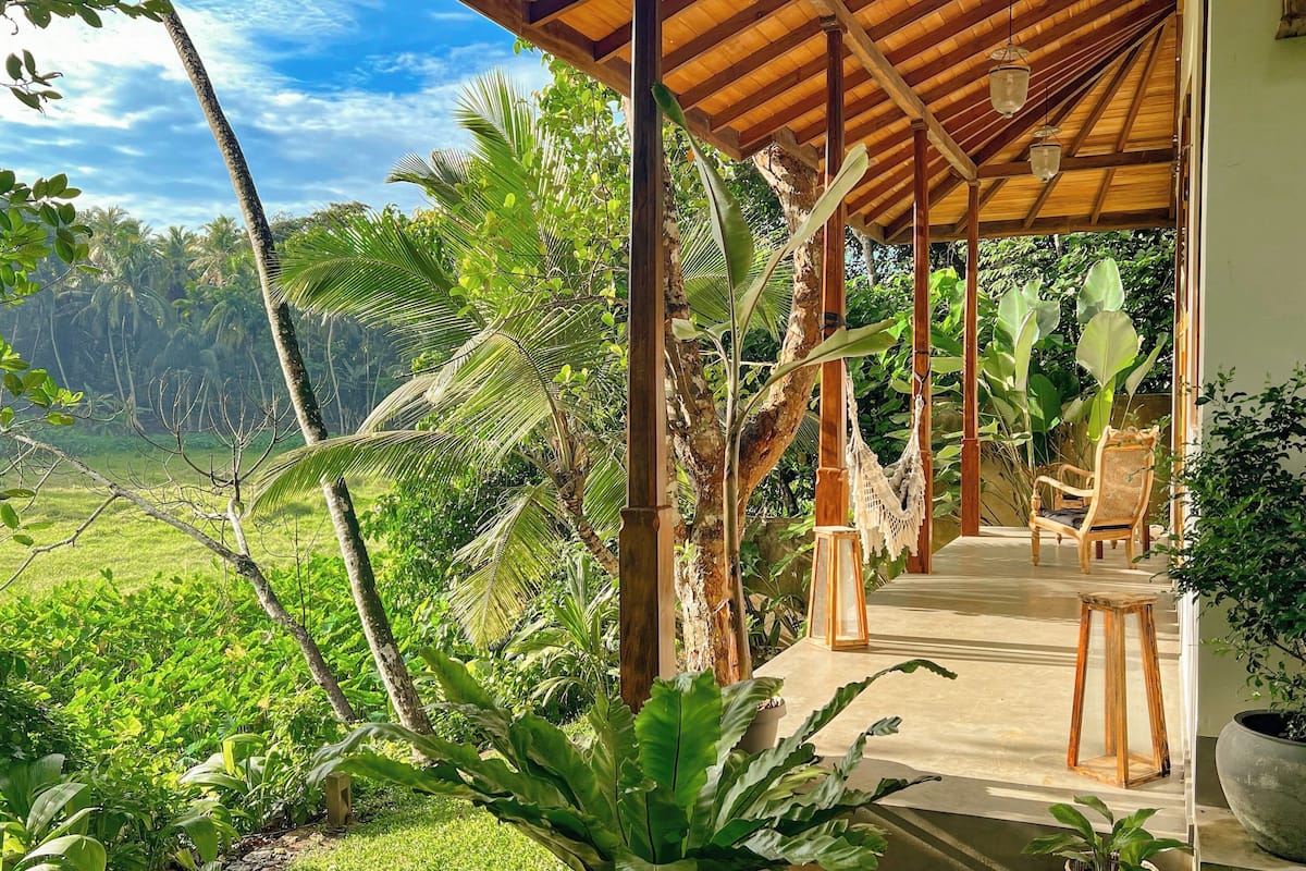 A covered outdoor seating area with a view of a lush landscape.