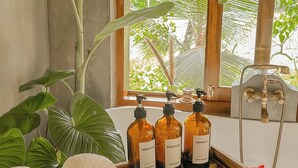A wooden table with three bottles of shampoo, a showerhead, and towels with flowers. - The Jungle Loft - Galle (Galle)