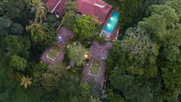Una vista aerea di una zona residenziale con diverse case, una piscina e rigogliosa vegetazione.