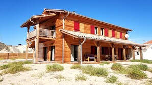 Een houten huis met twee verdiepingen, een balkon, rode luiken en een overdekte veranda.