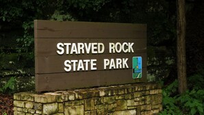A wooden sign for Starved Rock State Park with a map icon.