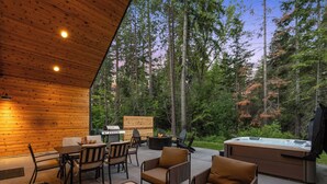 Une terrasse extérieure avec des murs en bois, un barbecue, des chaises et un jacuzzi.
