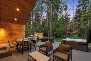 Eine Terrasse im Freien mit Holzwänden, einem Grill, Stühlen und einem Whirlpool.