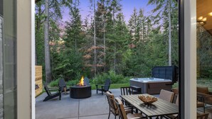Une terrasse extérieure avec un foyer, des fauteuils Adirondack, un jacuzzi et une table à manger.