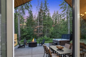 Eine Terrasse im Freien mit Feuerschale, Adirondack-Stühlen, Whirlpool und Esstisch.
