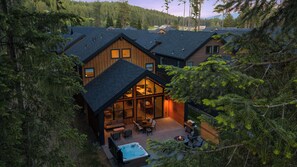 Eine Blockhütte mit einer großen Terrasse, einem Whirlpool und einem Essbereich.
