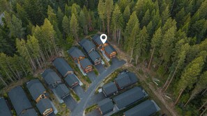 An aerial view of a residential area with multiple houses, surrounded by dense forest.
