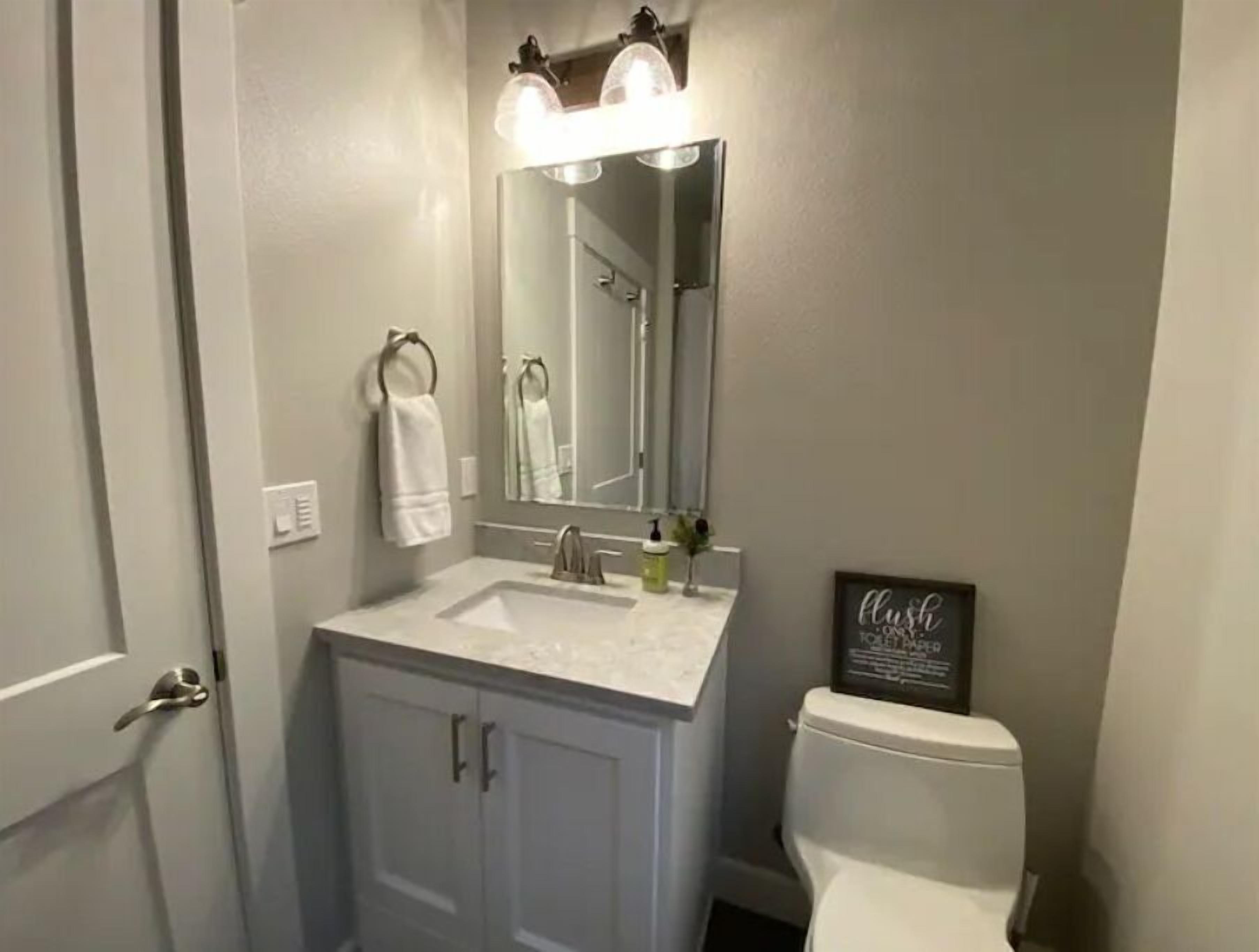 Een badkamer met een wit wastafel, een spiegel en een toilet.