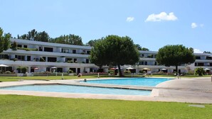Ein Hotel mit Schwimmbad, Sitzgelegenheiten im Freien und einem gepflegten Rasen.