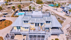 Une grande maison à plusieurs étages, située en bord de mer, dotée d’une piscine, d’un espace salon extérieur et d’une terrasse.