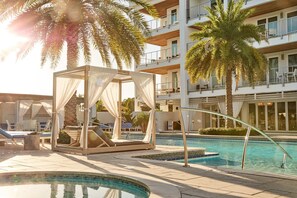 A poolside area with a cabana, lounge chairs, and a multi-story building in the background. - Unit 342 @ The Pointe | Resort Pool + Hot Tub | Grills, Fire Pit, & Restaurant (Rosemary Beach)