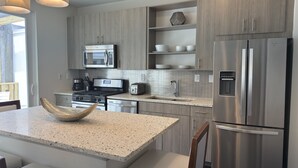 Una cocina moderna con encimeras de granito, electrodomésticos de acero inoxidable y armarios de madera.