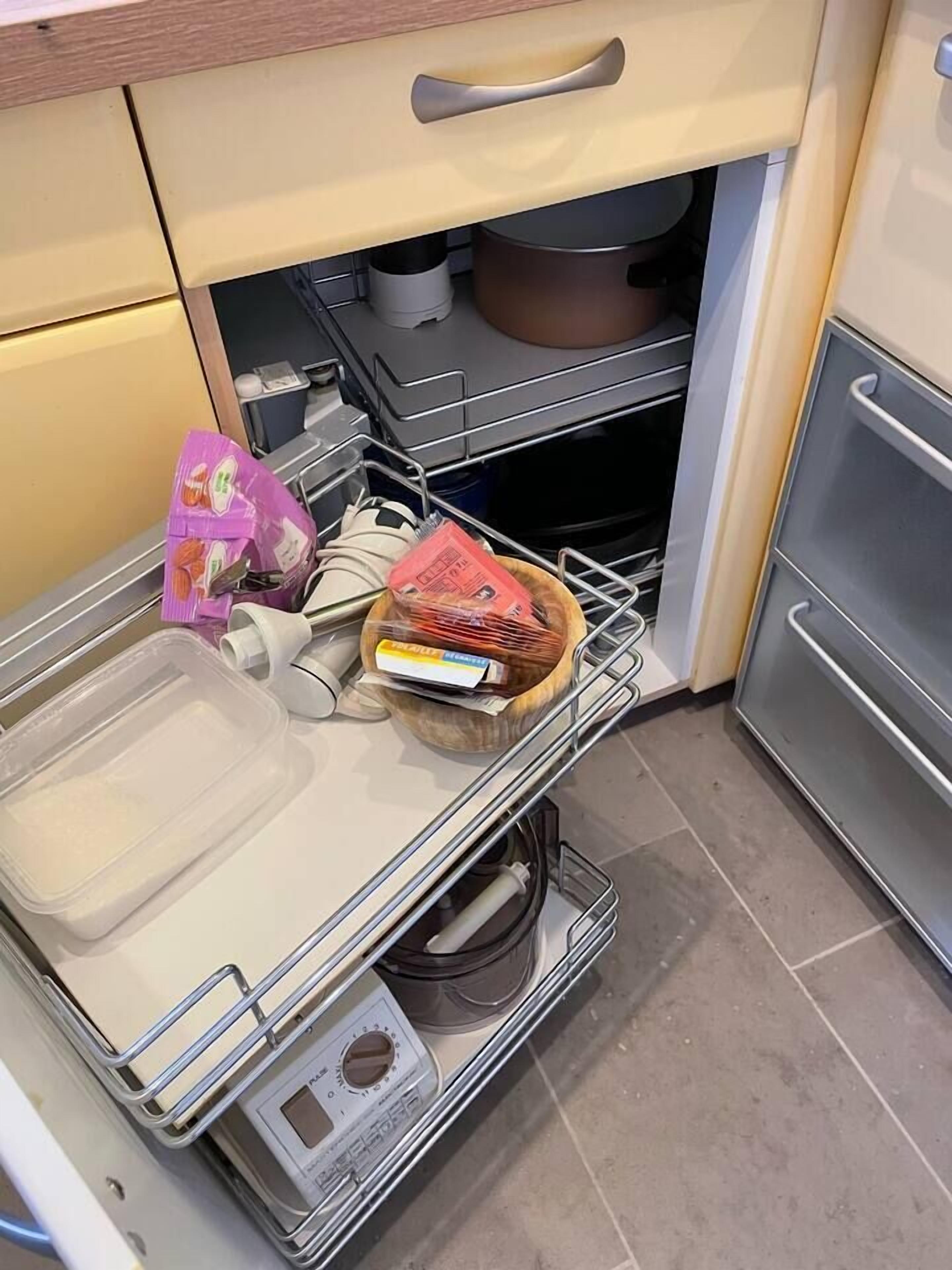 Une cuisine équipée d’un égouttoir, d’un saladier en bois et d’un récipient en plastique.