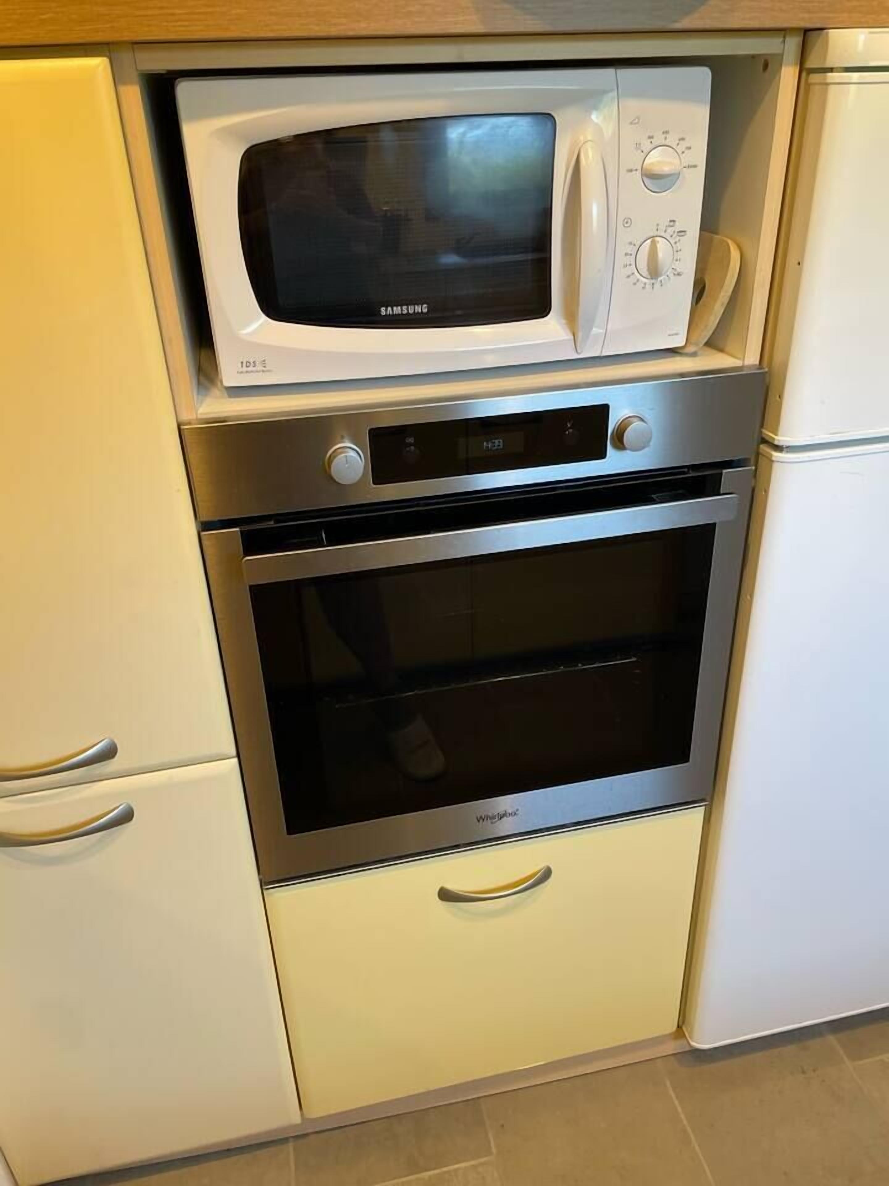A kitchen with a microwave, oven, and refrigerator.