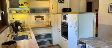 A compact kitchen with a sink, toaster, microwave, and oven.