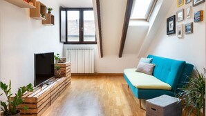 A modern living room with a blue sofa, wooden shelves, a flat-screen TV, and a skylight. - Cozy, bright, comfortable penthouse, 2 min from metro Dergano.  (Milano)