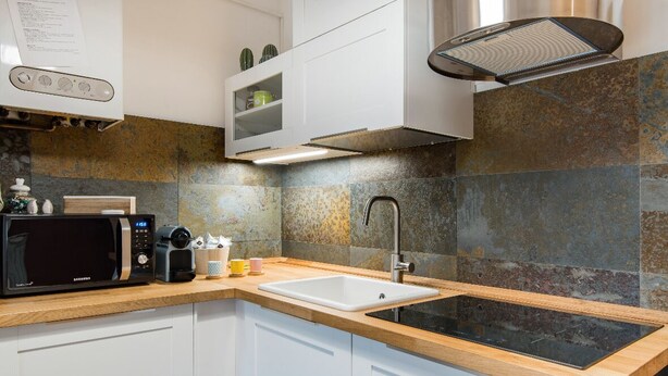 A modern kitchen with a microwave, sink, and stainless steel range hood. - Cozy, bright, comfortable penthouse, 2 min from metro Dergano.  (Milano)