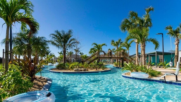 A pool area with palm trees, a wooden bridge, and lounge chairs. - Amazing Disney resort style & FREE Waterpark 2481 (Kissimmee)