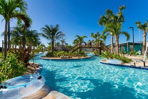 A pool area with palm trees, a wooden bridge, and lounge chairs.