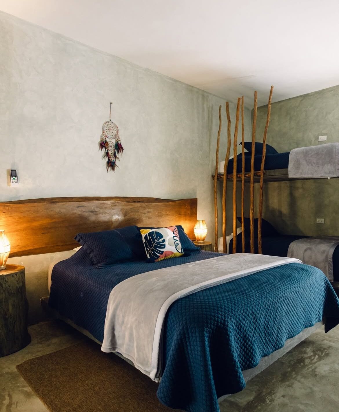 A bedroom with a bunk bed, a wooden headboard, a dreamcatcher, and two bedside lamps.