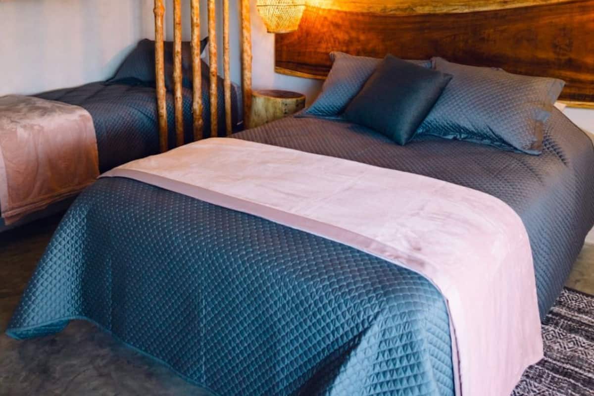 A bedroom with a bed, a bedside table, a hanging light, and a wall decoration.